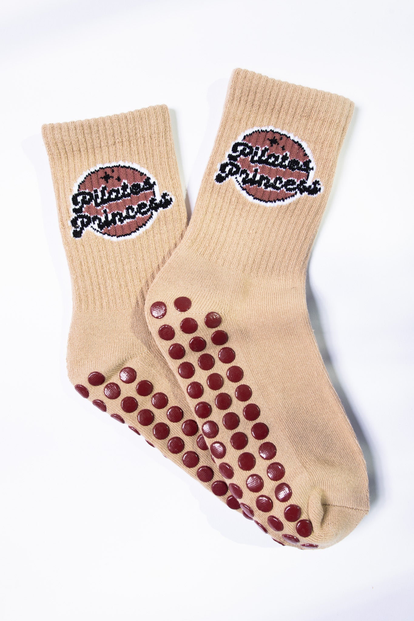 Flat lay of tan Pilates grip socks with non-slip grips and “Pilates Princess” logo, featuring chocolate-toned branding.